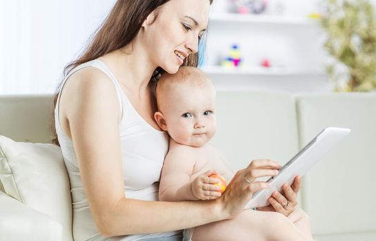 happy mother holding a year-old baby on his hands and shows her picture on digital tablet