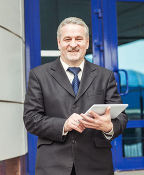 businessman with digital tablet stands on the background of a modern office building