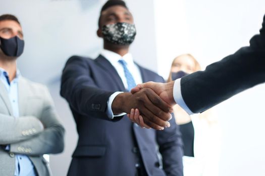 Business people in protective masks shaking hands, finishing up a meeting