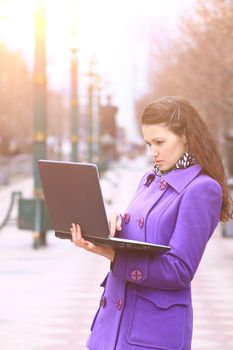 Beautiful girl with a laptop outdoors on a sunny day