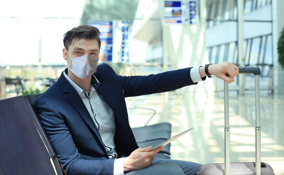 Businessman in protective mask with suitcase in hall of airport. Airport in the coronavirus epidemic