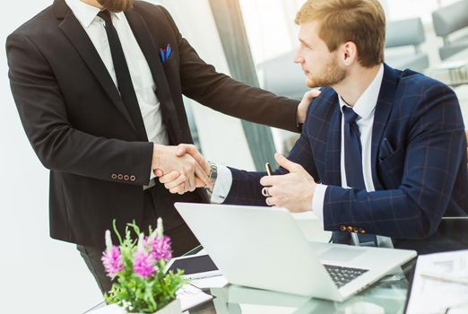 handshake between colleagues in the workplace in a modern office.the photo has a empty space for your text