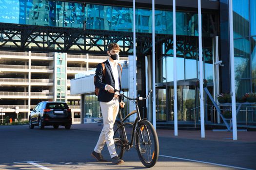 Handsome man in protective mask riding a bicycle to find job