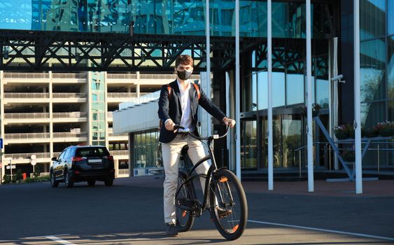 Handsome man in protective mask riding a bicycle to find job