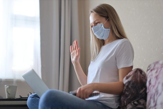 Young woman in medical mask works from home during self isolation and quarantine. Work online and stay at home. Coronavirus outbreak, flu epidemic and covid-19