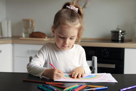 Girl painting rainbow at home, a symbol of UK National Health Service (NHS). Thanks to the doctors for their work. Stay at home Social media campaign