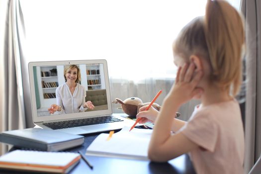 Distance learning. Cheerful little girl using laptop computer studying through online e-learning system