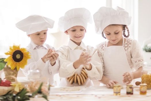 Happy little children in the shape of a chef to prepare tasty dishes in the kitchen