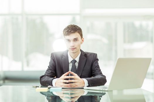 businessman sitting at a Desk before an open laptop.the photo has a empty space for your text