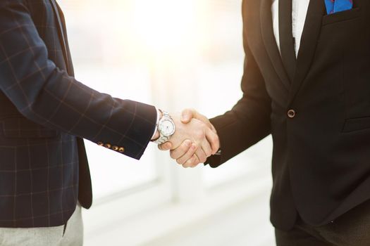 in the foreground - handshake of business partners on background of window in modern office.the photo has a empty space for your text