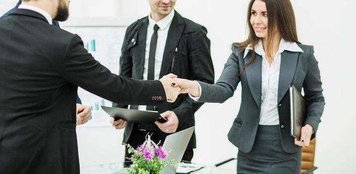 closeup of a successful handshake business partners after signing the contract in the workplace in a modern office