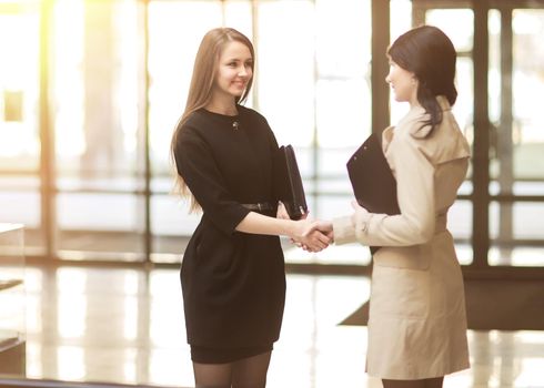 handshake of the company manager and the client in the lobby of the modern office. The photo has an empty space for your text