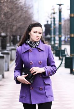 Beautiful girl in a coat on the street with a bag in autumn
