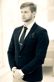 photo in retro style - beginner businessman in a business suit stands near the window, hands folded in front of him .the photo has a empty space for your text