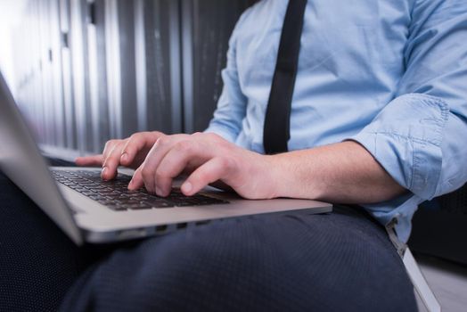 Male IT engineer working on a laptop in server room at modern data center