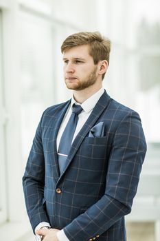 newcomer businessman in a business suit stands near the window, hands folded in front of him .the photo has a empty space for your text