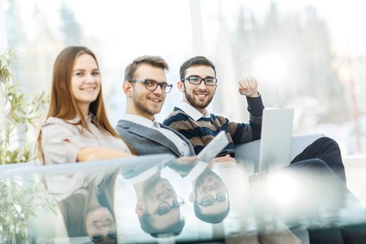 professional business team sitting near the transparent table on a light background.the photo has a empty space for your text.