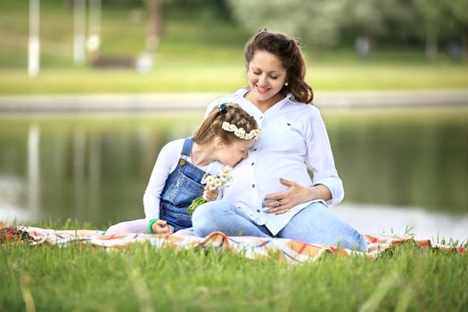 pregnant mother and little daughter having a picnic in the Park on a Sunny day. the photo has a empty space for your text