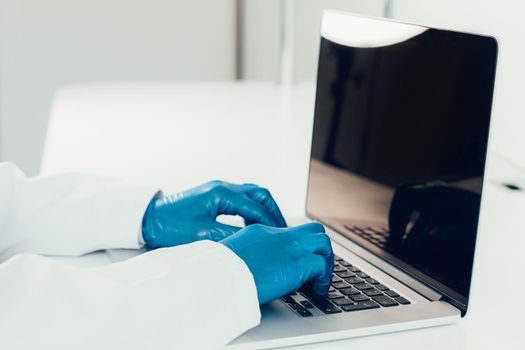 close up. doctor in protective gloves typing on a laptop . the concept of telemedicine.