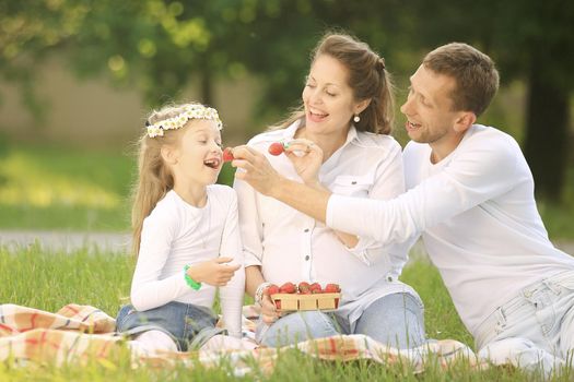 pregnant mother,happy father and daughter on a picnic in the Park on Sunday