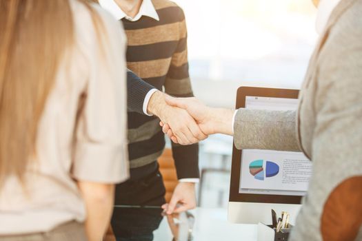 handshake between the client and the Manager of the company near the workplace in the modern office.