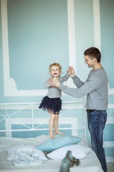 loving father plays with happy little daughter on the bed in the bedroom