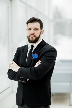 portrait of successful businessman standing near a window in bright office.the photo has a empty space for your text