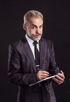 businessman with pen and papers ready for signature on a black background.the photo has a empty space for your text