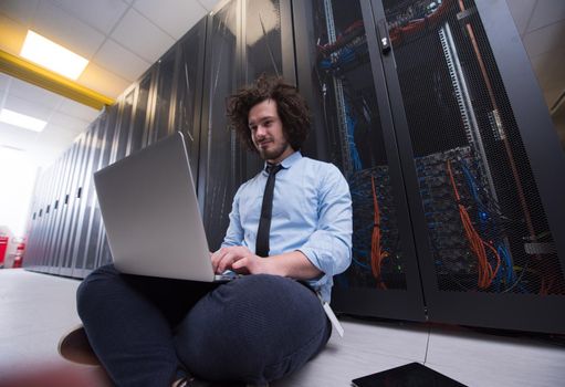 Male IT engineer working on a laptop in server room at modern data center