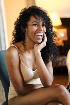 Young smiling afro american woman wearing underwear and sitting in bedroom. Concept of relax and beauty.