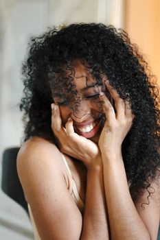 Close up portrait of smiling black girl with curly hair. Concept of afro american beauty and female person.