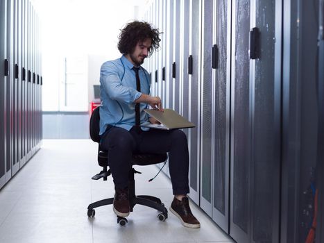 Male IT engineer working on a laptop in server room at modern data center