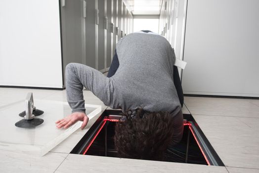 young IT engineer connecting cables in server room at modern data center