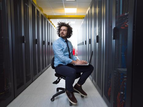 Male IT engineer working on a laptop in server room at modern data center