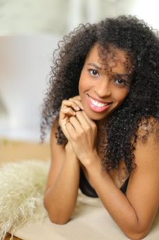 Young cute afro american woman lying leaning on elbows and wearing bra. Concept of underwear portrait and home photo session.