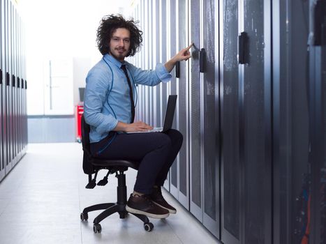 Male IT engineer working on a laptop in server room at modern data center