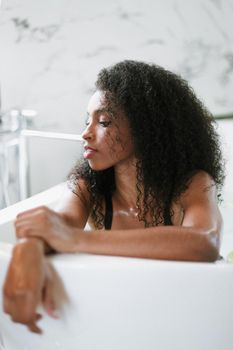 Young brown skin woman lying in barth and wearing black underwear. Concept of personal care and relax.