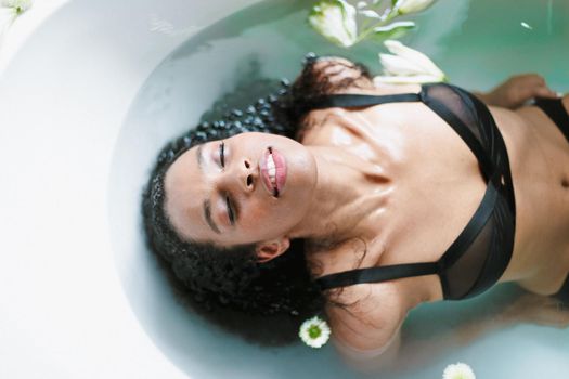 Young brown skin girl taking bath and wearing swimsuit. Concept of relax and spa.
