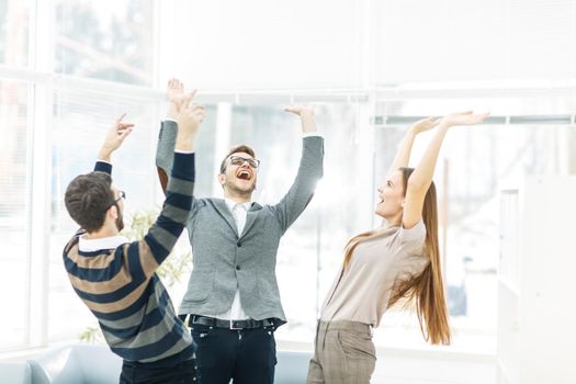 jubilant business team standing in a circle, hands up in rejoice success.the photo has a empty space for your text.