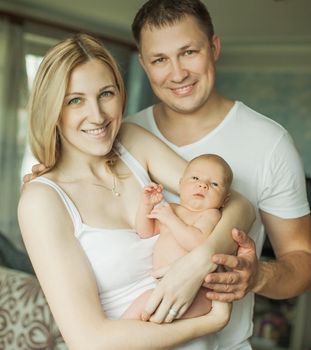 concept of family happiness - portrait of happy parents and newborn infant