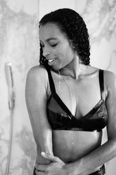 Black and white photo of afro american woman wearing swimwear and standing in bathroom. Concept of beauty and fashion.