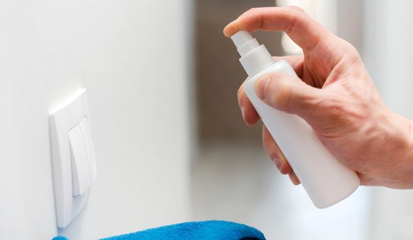 close up. employee treating the wall switch with an antibacterial spray. photo with a copy-space.