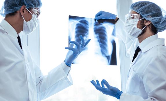 close up. scientists in protective masks looking at an x-ray of the lungs . concept of health care.
