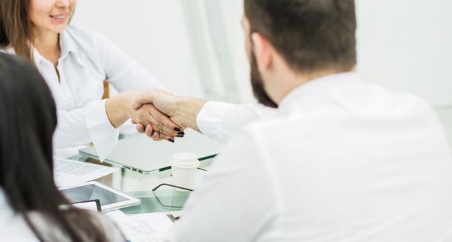 closeup of a handshake between the Manager and the client after the signing of the financial agreement in the workplace in the office