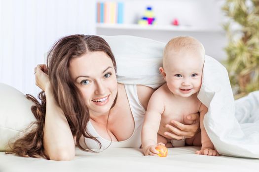 happy mother and her year-old child playing on the sofa in the bedroom