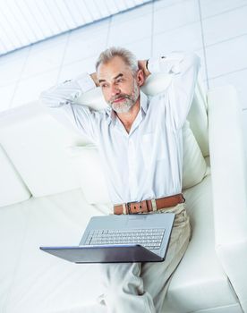 top view of successful businessman working on laptop sitting on sofa in modern office.