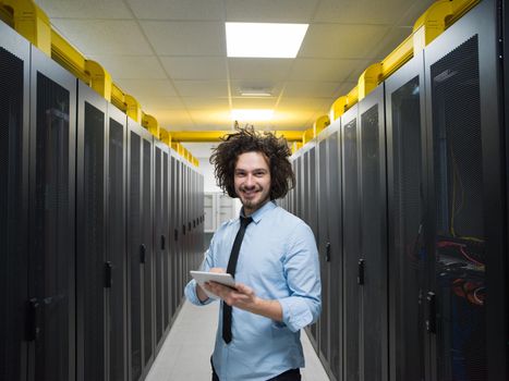 Male IT engineer working on a tablet computer in server room at modern data center