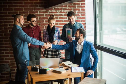 business team and the Manager with a handshake greeted the customer in a modern office