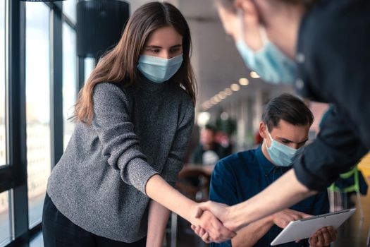 close up. young staff in protective masks shaking hands with each other .