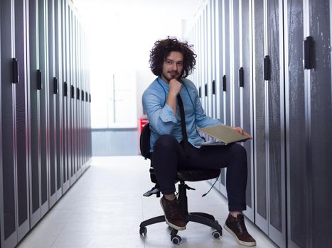 Male IT engineer working on a laptop in server room at modern data center